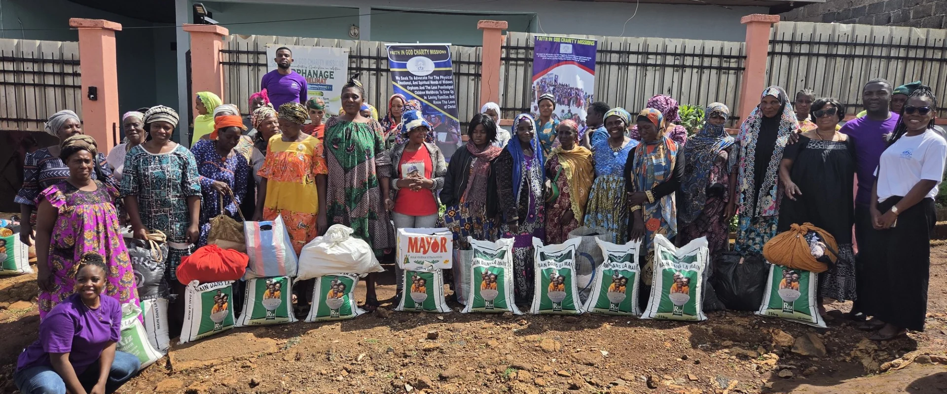 A large group gathered behind bags of food at an FIGCM distribution event.