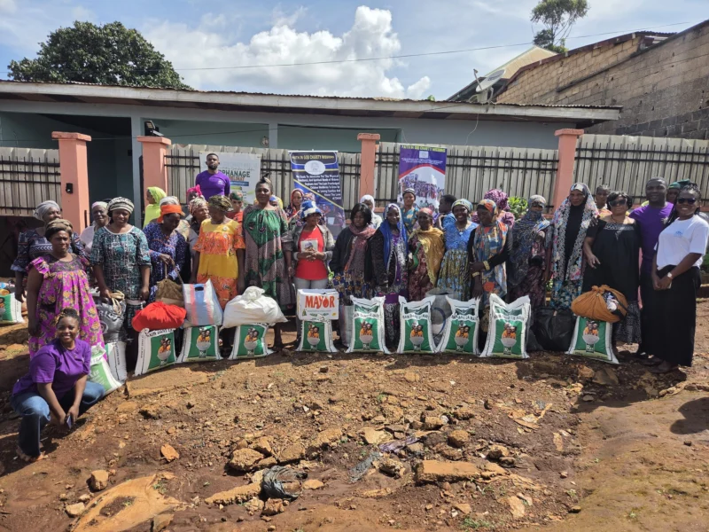 A large group gathered behind bags of food at an FIGCM distribution event.