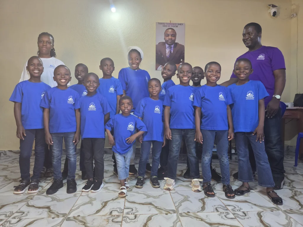 Children and staff in blue Faith in God Charity Missions shirts gathered together indoors.