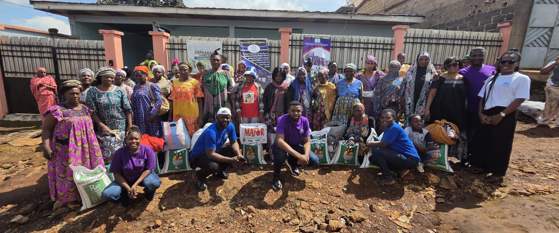 FIGCM staff and volunteers with community members gathered behind bags of food at a distribution.