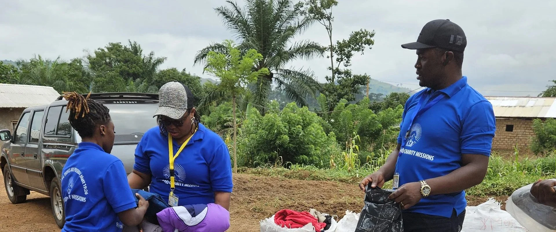 FIGCM team members sorting donated clothing at a community distribution, beside a pickup truck.